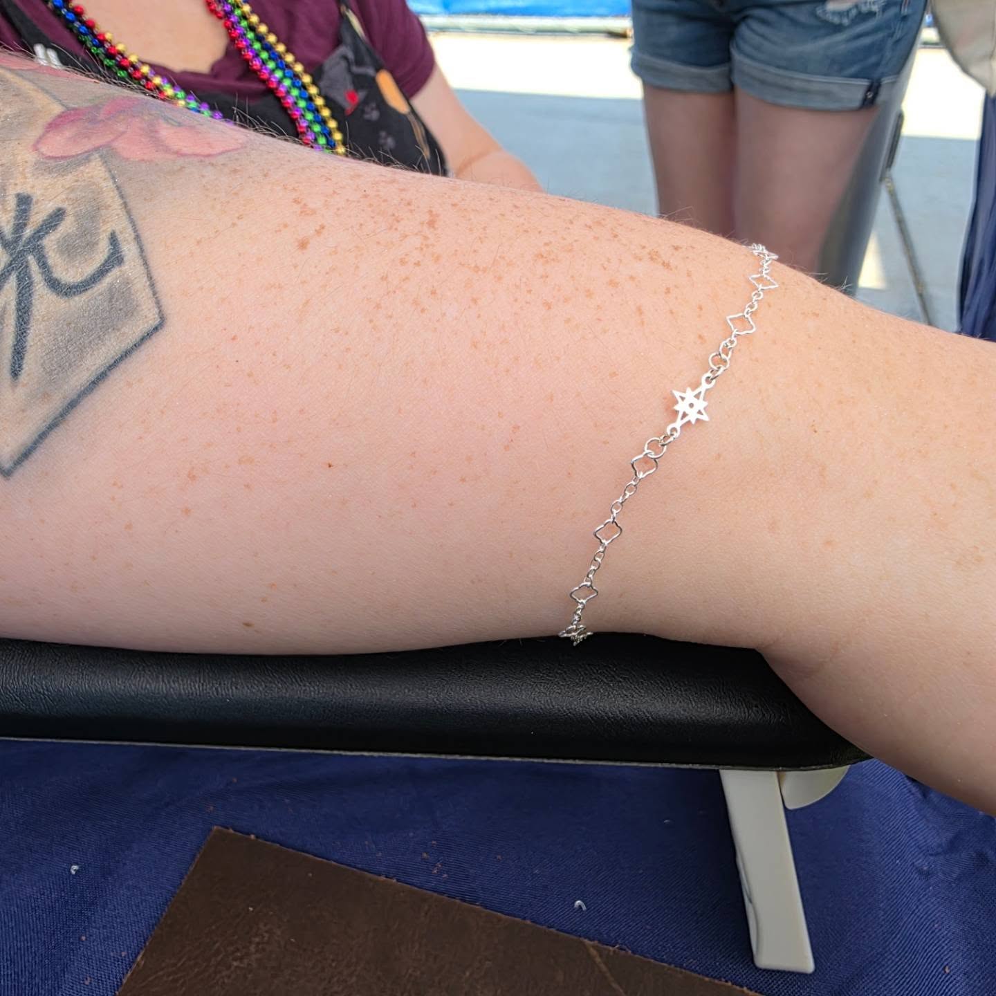 A bracelet with clover links and a North Star connector on a wrist