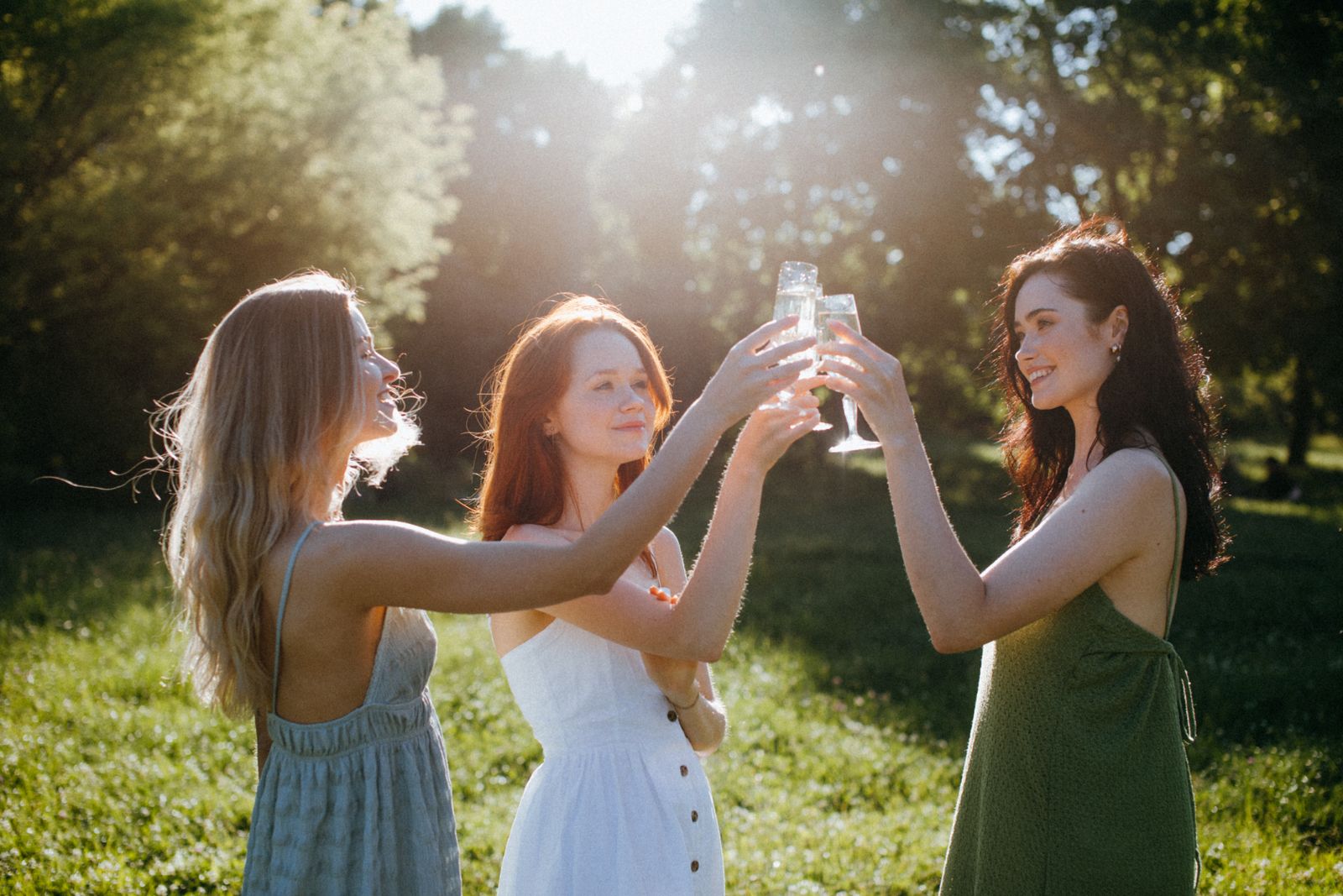 Three friends raising glasses together outdoors