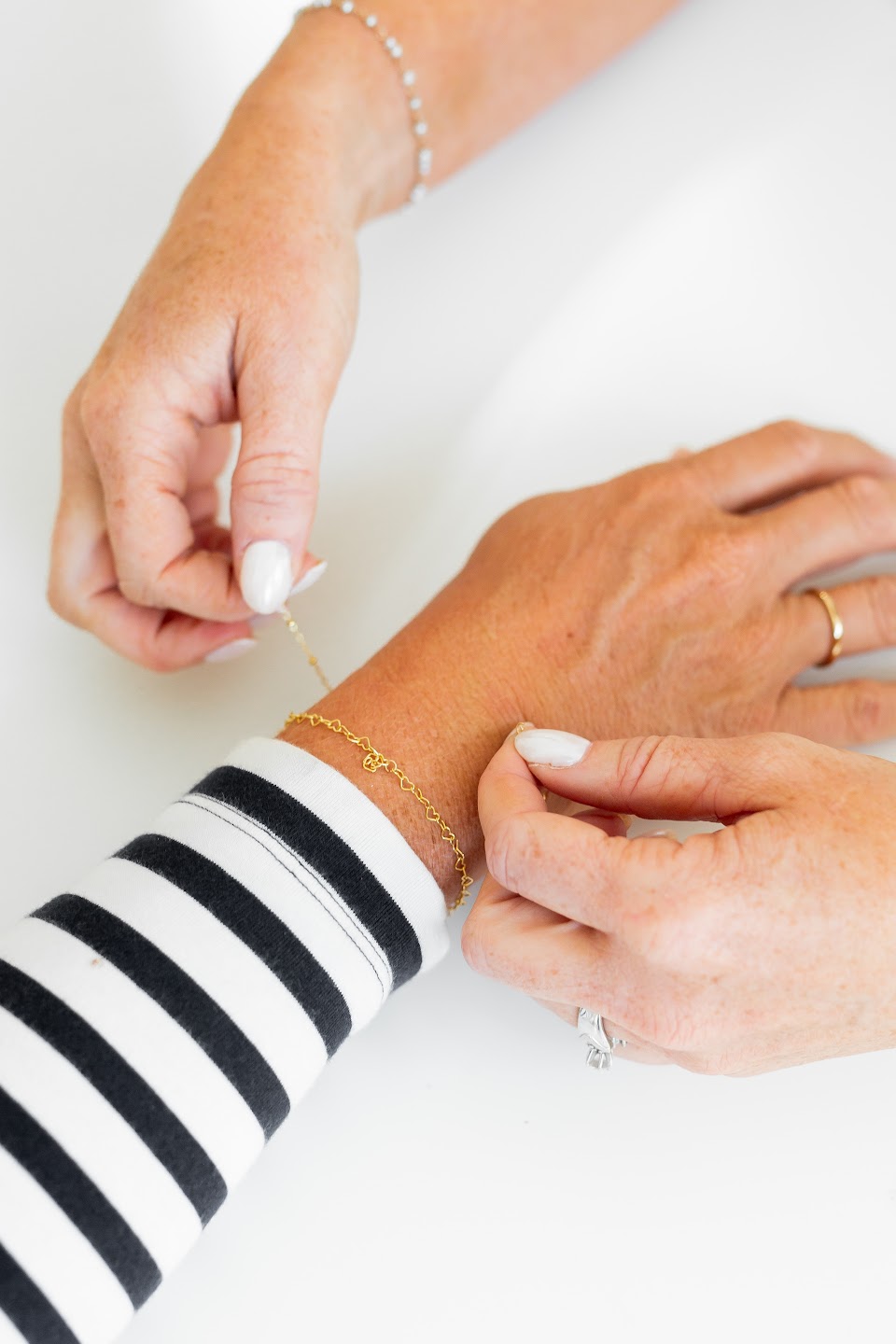 Hands checking the length of a delicate bracelet around a wrist