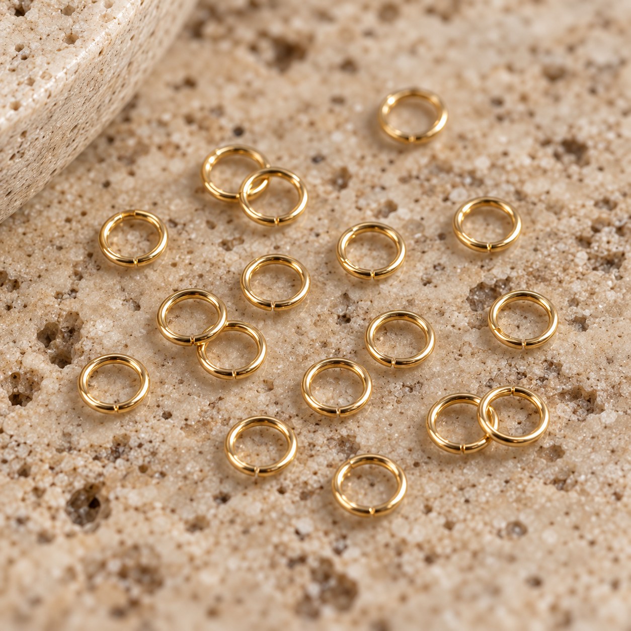 Close view of 14K gold-filled jump rings representing 24g wire on travertine.