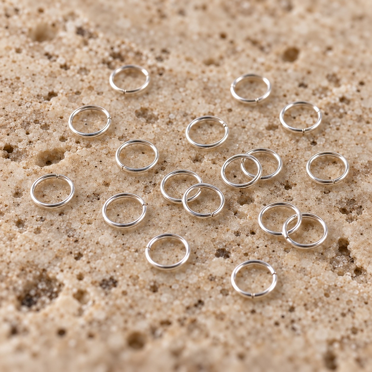 Close view of sterling silver jump rings representing 26g wire on travertine.