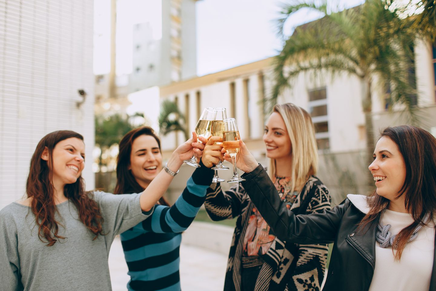 Four friends raising a toast at an outdoor daytime celebration