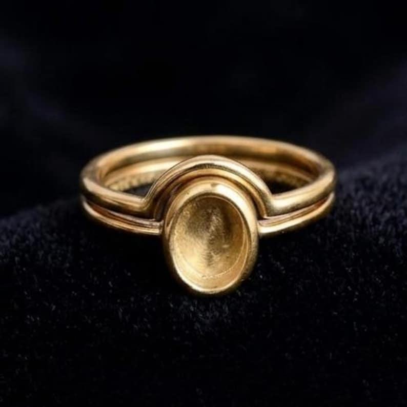 Supplier photo of an empty gold-finish oval ring setting and curved companion band